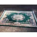 A Chinese thick pile carpet woven with central oval floral medallion on green field framed by