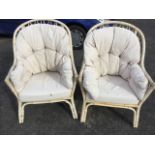 A pair of button upholstered cane armchairs with loose cushions, having latticework backs and