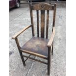 An oak armchair with arched back rail carved with roundel above splats, with curved arms above a