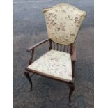 An art nouveau upholstered mahogany armchair with shield shaped back and curved arms above a