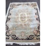 A large Chinese carpet woven with rectangular rounded floral medallion on fawn field bordered by