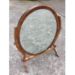 An oval nineteenth century mahogany dressing table mirror, the plate in crossbanded frame on