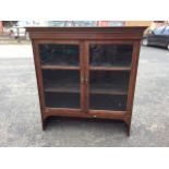 A glazed mahogany cabinet with moulded dentil cornice above chamfered doors enclosing shelves,