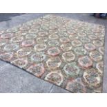 A large Wilton style carpet woven with grid of joined hexagonal floral medallions in pink, pale