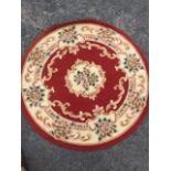 A circular rug woven with central ivory floral panel and conforming frieze on pink ground with