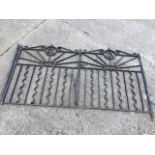 A pair of wrought iron driveway gates, each having circular scrolled medallions above sunbursts,