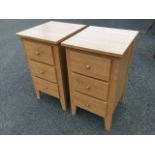 A pair of modern bedside cabinets, each with three knobbed drawers raised on angled legs. (17in x
