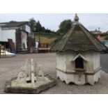 An hexagonal dovecote with turned finial above a pitched boarded roof, having three apertures with