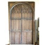 A massive Victorian carved oak doorway with arched frame around a pair of gothic panelled doors with