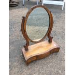 A nineteenth century oval mahogany dressing table mirror on shaped supports, above a serpentine