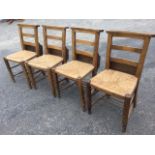 A set of four rush seated church chairs by West & Collier Ltd, the ladderbacks with hymn book