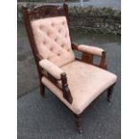 A late Victorian upholstered walnut armchair, the button upholstered back with leaf carved