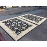 A pair of contemporary rugs woven with entwined foliage on black fields, framed by fawn friezes with