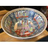 A large circular famille rose style bowl decorated with scrolled figural panels on blue floral