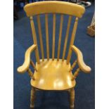 A beech slatback farmhouse armchair with shaped arms on spindles, the solid seat on turned legs &