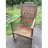 A Victorian carved oak armchair, the back with roundel framed by foliate carved panels bordered by