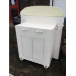 A painted metal cabinet on casters, with arched back panel above a cupboard with two doors. (41.
