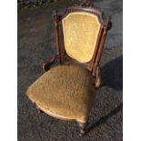 A Victorian carved walnut nursing chair, the shield shaped upholstered back having scroll carved