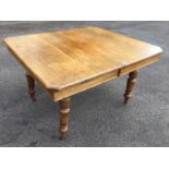 A rectangular extending oak dining table with spare leaf, the top with canted corners, raised on