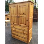 A reproduction pine press cupboard, the top with fielded panelled chamfered doors above four long