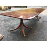 A Georgian style twin pedestal mahogany dining table, the top with two spare leaves on tapering