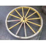 A large antique ash agricultural wheel with thick forged metal rim and chamfered spokes around a hub