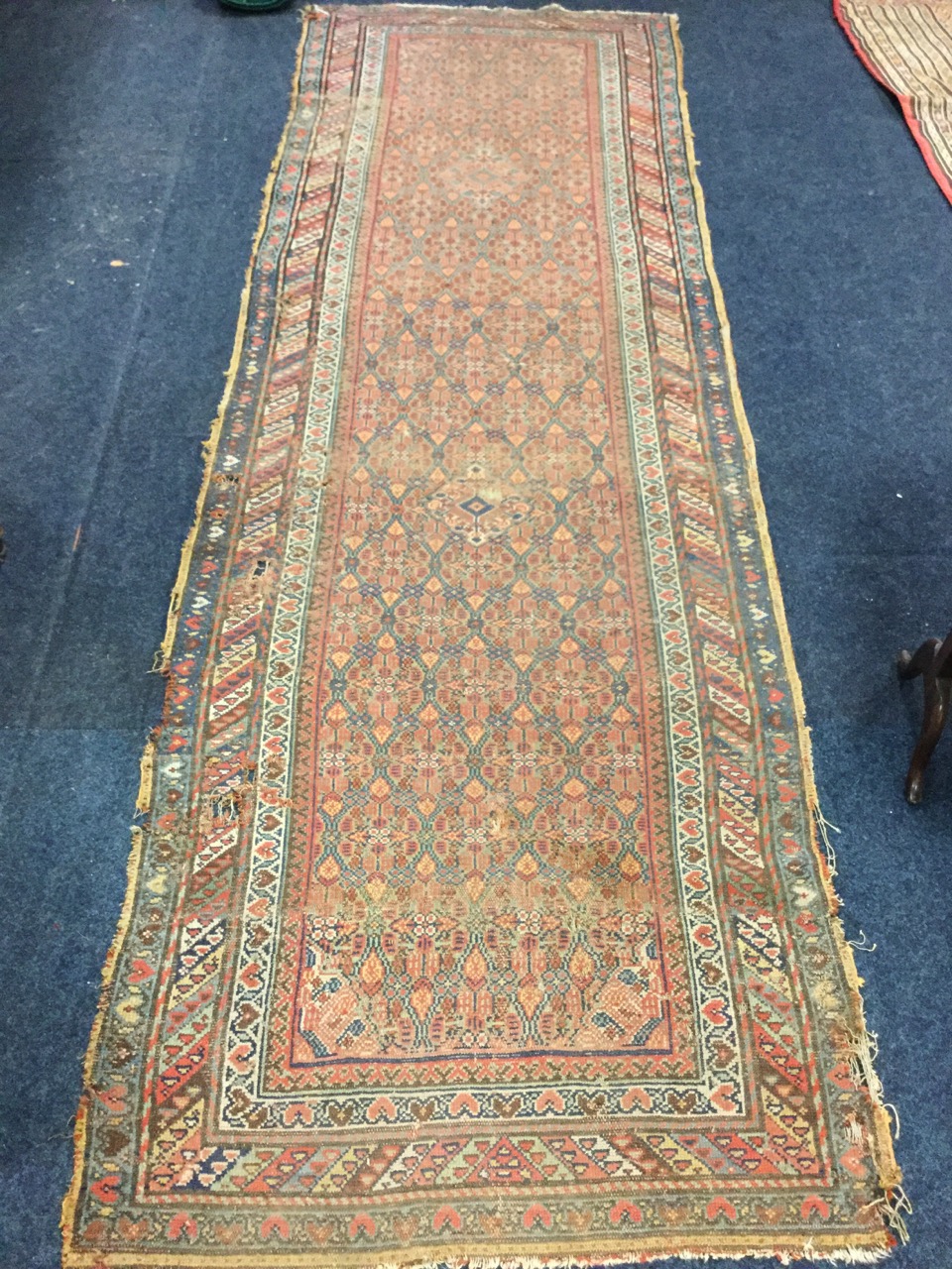 An antique Indian runner, the field woven with two lozenges in floral grid on madder ground,