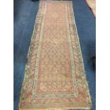 An antique Indian runner, the field woven with two lozenges in floral grid on madder ground,