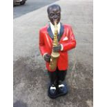 A painted resin/composition half-size figure of a saxophone player on shaped plinth. (41in)