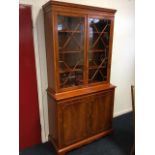 A nineteenth century style yew bookcase with moulded dentil cornice above astragal glazed doors