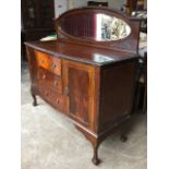 A late Victorian mahogany sideboard with gadrooned carving, the arched back with oval bevelled