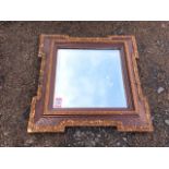A square Victorian bevelled mirror, the plate in oak frame of re-entrant outline having applied gilt