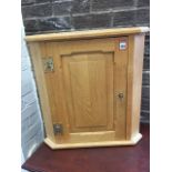A craftsman made oak corner cabinet with moulded cornice above fielded panelled door mounted with