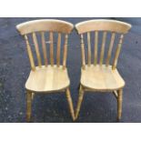 A pair of beech slatback kitchen chairs with solid seats raised on turned legs & stretchers. (2)