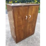 A 50s walnut compactum, the crossbanded doors with bakelite scrolled handles enclosing a fitted