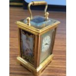 A miniature brass carriage clock mounted with Sevres style panels decorated with cherubs, the