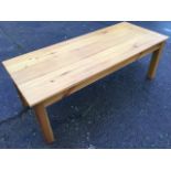A modern pine coffee table, the rectangular top on square column legs. (53.75in x 22in x 18.75in)