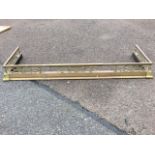 A telescopic brass fender, with square rail on pierced fretwork grill supports on a moulded curb,