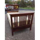 An Edwardian walnut single bed, the headboard & tailboard with lathes beneath moulded rails, the