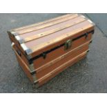 A domed top seamans chest, the trunk mounted with slats on canvas covered ground, having lined