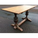 A rectangular oak dining table having twin acanthus carved bollection columns on sledge feet