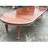 A rectangular rounded extending mahogany dining table with four leaves and 'D' shaped ends, the