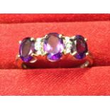 A 9ct gold amethyst and diamond ring with three oval claw set amethysts framing two small diamonds -
