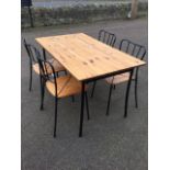 A contemporary pine dining table with four matching chairs, the rectangular table on angled metal