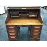 An Edwardian oak rolltop desk, the tambour enclosing pigeonholes and drawers above a frieze drawer