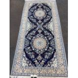 A rectangular Iranian rug woven with two floral star medallions on blue field framed by floral