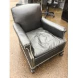 A leather upholstered armchair, the padded back and arms with brass studding, having loose cushion