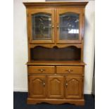 An oak kitchen dresser with moulded dentil cornice above a pair of arched leaded acid etched glass