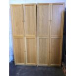 A pair of contemporary honey oak cupboards, each with four panelled doors enclosing adjustable