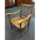 A Derbyshire style oak armchair, the back with spindles having scroll carved shaped arms on turned